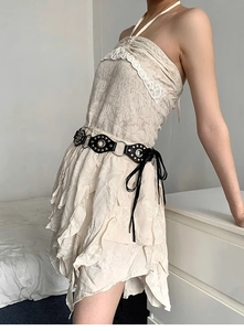 Detail of Y2K punk belt with metal rings and fringe ties on a beige lace dress