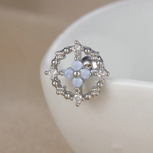 Détail macro du piercing papillon avec opales bleues et bordure en argent perlé