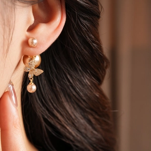 Macro side view of vintage gold-plated butterfly earrings with sparkling zircon and pearls