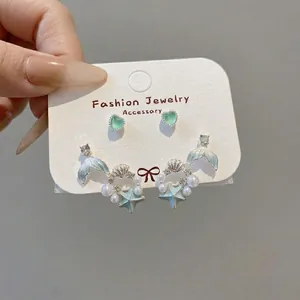 Detail of ocean-themed earring set with sea star, shell charms and pearl hoop earrings