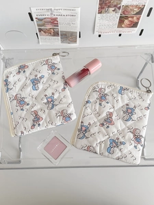 Détail de pochettes en coton matelassé avec imprimé dessin animé vintage et zip à anneau métal