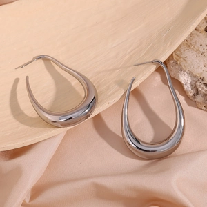 Detailed close-up of polished silver hollow U-shaped drop earrings on silk fabric