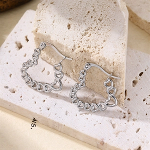 Vue macro de boucles d'oreilles créoles ajourées en forme de cœur sur pierre beige
