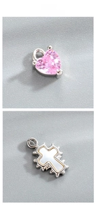 Detailed close-up of pink heart zircon and vintage white enamel cross charms for DIY jewelry