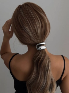 Detail of a silver sculptural double oval metal hair clip on a low ponytail hairstyle