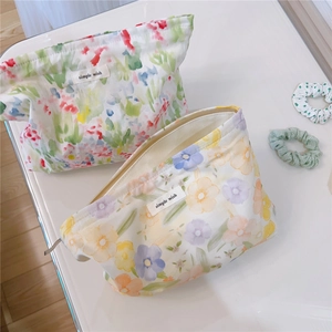 Close-up of floral cotton makeup bags with zippers and simple wish labels on white surface