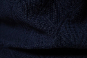Macro shot of dark blue knit fabric showing detailed diamond jacquard texture on sweater