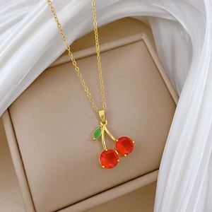 Gros plan du pendentif cerise avec cristaux rouges sur boîte à bijoux beige élégante