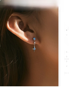 Gros plan d'une boucle d'oreille en argent s925 avec pierre bleue et étoile sur l'oreille