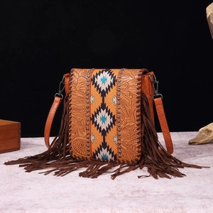 Detailed close-up of bohemian leather crossbody bag with vintage floral embossing and fringe