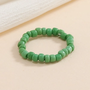 Vista dall'alto di un anello elastico con perline verde brillante su sfondo neutro