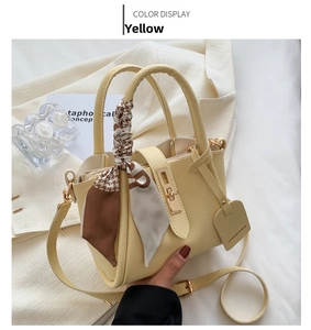 Détail macro du sac seau jaune en cuir avec fermoir doré et accessoire de foulard en soie
