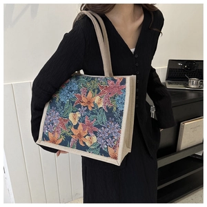Detail of vintage floral print tote bag featuring colorful leaves and sturdy handles