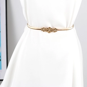 Detail der eleganten goldenen Blumenschnalle an elastischem Metallgürtel für Damen