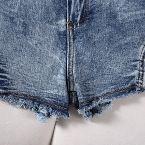 Primer plano detallado de shorts vaqueros azules con dobladillo deshilachado y costuras