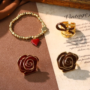 Detail of red rose earrings and brown bow ring set on vintage script background