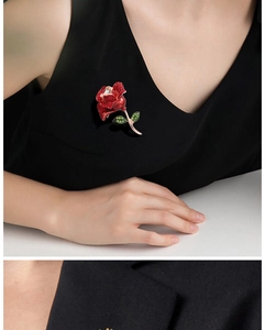 Close-up of red rose brooch with green leaves, gold plating and sparkling crystals