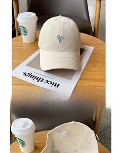 Detailed interior of cream baseball cap showing sweatband and heart embroidery texture