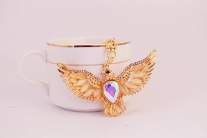 Detail of a golden eagle keychain featuring sparkling rhinestones and a lobster clasp