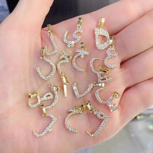 Close-up of assorted gold-plated Arabic letter pendants with pavé cubic zirconia inlay