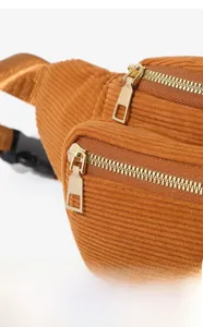 Detail of caramel corduroy waist bag showing ribbed fabric texture and golden zippers