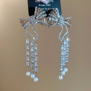 Macro shot of silver bow earrings with rhinestone fringe and white pearl drops