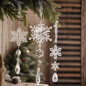 Set of transparent snowflake ornaments hanging on green pine branches for Christmas decor