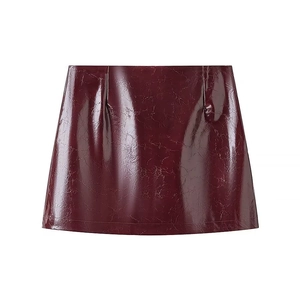 Détail de la mini-jupe en similicuir bordeaux avec une texture brillante effet craquelé