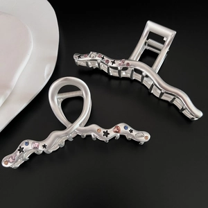 Detail of matte silver star hair claws with colorful zircon and cross-wrap design
