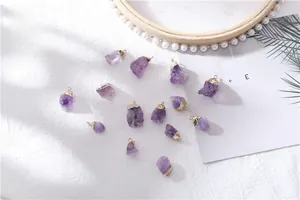 Macro shot of natural raw amethyst crystal pendants with elegant gold plated edging