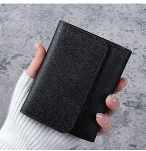Close-up of black litchi texture on a minimalist short bi-fold leather wallet for women