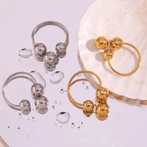 Detailed close-up of 18K gold and silver hoop earrings with metal beads on a mirror