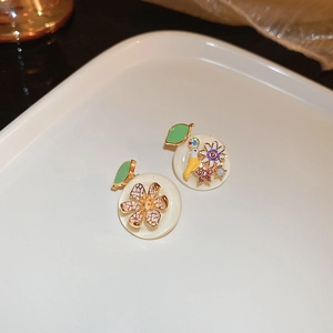 Détail de boucles d'oreilles florales avec pétales en émail rose et cristaux colorés