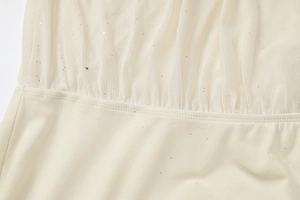 Makrodetail aus beige Netzstoff mit glitzerndem Glitzer und feinen Nähten am Kleid