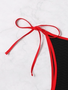 Close-up of textured black fabric with red piping and elegant side-tie bow detail