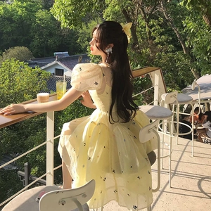 Outdoor shot of a light yellow floral dress featuring puff sleeves and a flowing hemline