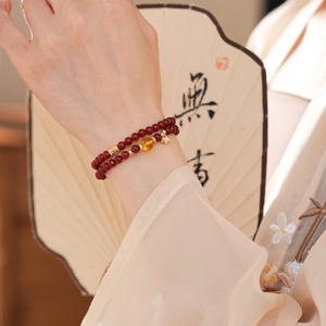 Vue détaillée d'un bracelet double en agate rouge et breloques en or 18k au poignet
