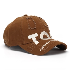 Detailed side view of distressed brown baseball cap with embroidered letters and torn edges