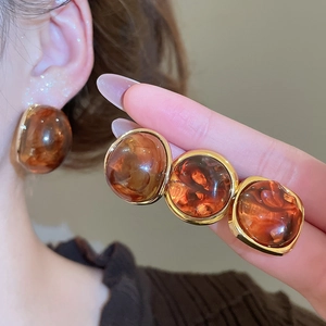 Detailed view of vintage amber resin earrings with elegant gold metal edging for women