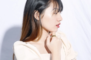 Close-up of a gold Roman numeral cutout ring worn by a model in a minimalist style