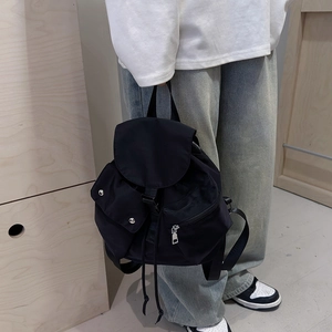 Detail of a black nylon backpack with two front pockets and silver metal buckles