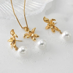 Golden flower jewelry set with white pearls including necklace and earrings on white foam