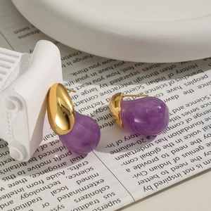 Elegant gold drop earrings with purple translucent waterdrop charms on vintage newspaper