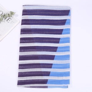 Close-up of striped cotton linen scarf with tassels on a white minimalist background