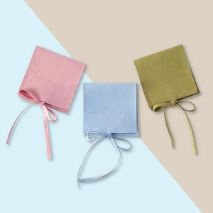 Three elegant microfiber jewelry pouches in pink, light blue, and olive green with ribbons