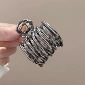 Detail of dark grey metal hair claw clip with abstract coiled lines for high ponytail