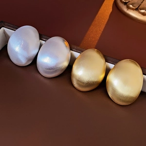 Vue détaillée des boucles d'oreilles ovales en métal brossé, finitions or et argent