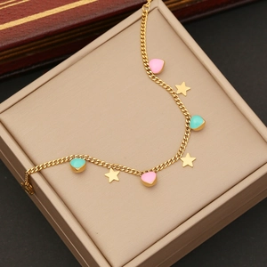 Detail of gold chain with pink and cyan enamel hearts and gold star charms on a jewelry box