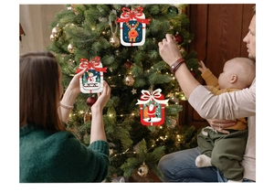 Famille décorant le sapin avec des ornements en bois de renne et bonhomme de neige