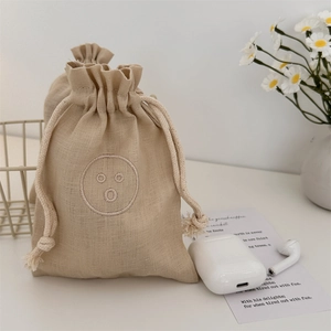 Detailed macro view of linen drawstring pouch with minimalist smiley face embroidery